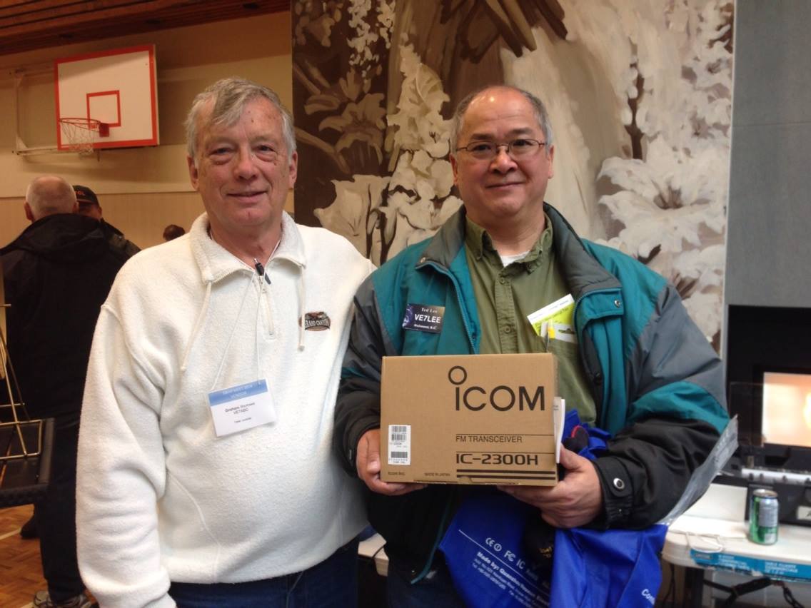 Graham, VE7ABC, President of the Burnaby Amateur Radio Club, presenting an Icom IC-2300H raffle prize to Ted Lee, VE7LEE, at the 2014 swap meet in New Westminster, British Columbia